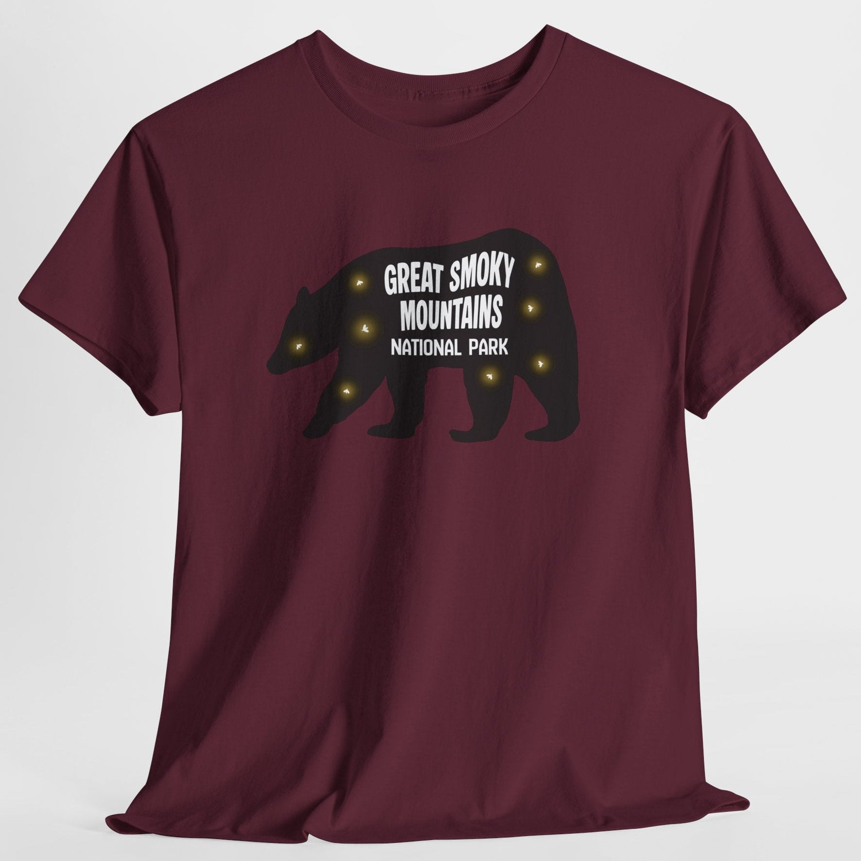 A maroon short-sleeve crewneck t-shirt featuring a black bear silhouette graphic on the chest with the text 'GREAT SMOKY MOUNTAINS NATIONAL PARK' in white and small fireflies