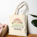 Beige tote bag with nature-themed design on a wooden surface with a plant in the background